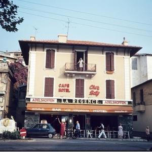 a building with a man sitting on a balcony at Hotel La Regence in Villefranche-sur-Mer