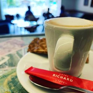 a cup of coffee on a plate with a red spoon at Hotel La Regence in Villefranche-sur-Mer