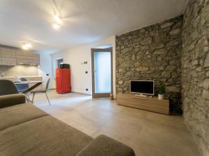 een woonkamer met een stenen muur en een televisie bij La Maison de Papagran CIR Charvensod-0007 in Aosta