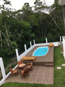a swimming pool with a deck and chairs and a table at Casa da Gina in Santa Cruz Cabrália