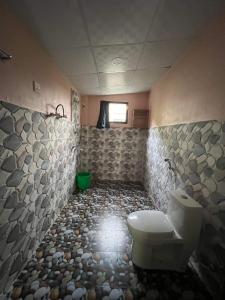 a bathroom with a toilet and a stone wall at Bardia Wildlife Resort in Bhurkīā