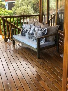 a bench on a porch with pillows on it at Adorable 2 bedroom seaside vacation home in Kleinmond