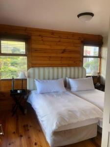 a bedroom with two white beds and a wooden wall at Adorable 2 bedroom seaside vacation home in Kleinmond