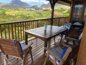 a wooden table and chairs on a porch with a grill at Adorable 2 bedroom seaside vacation home in Kleinmond