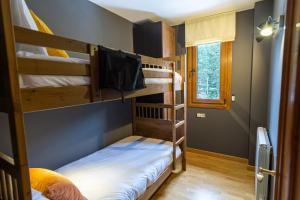 a room with three bunk beds and a television at TRES OSSOS Apartamento vacacional in La Molina