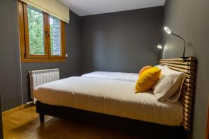 Un dormitorio con una cama con almohadas amarillas. en TRES OSSOS Apartamento vacacional, en La Molina