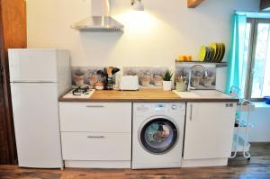 a kitchen with a washer and dryer under a counter at Mini Maison au Calme avec Coin Exterieur in Eygliers