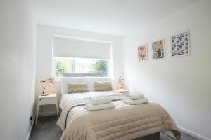 um quarto branco com uma cama grande e toalhas em Foxcroft em Brighouse