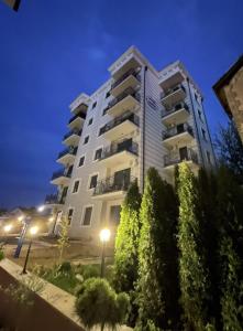a tall white building with trees in front of it at Apartman Kardaš in Vrnjačka Banja