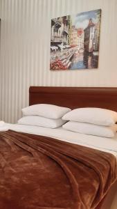 アドレルにあるHotel Nikaの白い枕と壁画付きのベッド