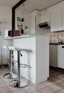 a kitchen with a white counter and stools at Hautes Roches - Magnifique vue sur la montagne in Crans-Montana