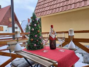 a table with two wine glasses and a christmas tree at Apartmani Vidatela Kopaonik in Kopaonik