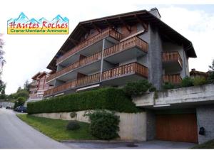 a large building with a fence next to a street at Hautes Roches - Magnifique vue sur la montagne in Crans-Montana +10 photos