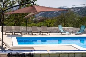 um pátio com cadeiras e um guarda-sol ao lado de uma piscina em B&M Rab-Lopar em Lopar