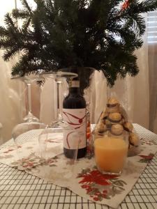 a table with a bottle of wine and a vase with a tree at Casa delle orchidee in Alba