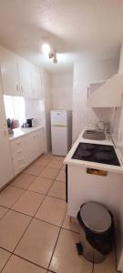 a white kitchen with a stove and a sink at Margate Boulevard Beachfront Apartment in Margate +1 photo