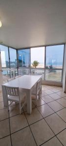 a white table and chairs in a room with windows at MARGATE BOULEVARD SPACIOUS APARTMENT in Margate