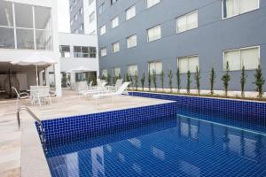 a swimming pool in front of a building at Hotel Abba Uno in Betim