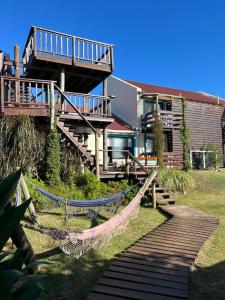 a house with a deck and a wooden walkway at Posada de la Viuda in Punta Del Diablo