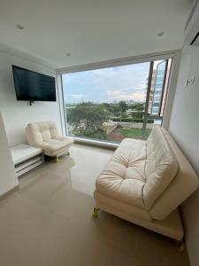 a living room with two chairs and a large window at Playa la Boquilla, Apto dentro Condominio Hotel Sonesta in Cartagena de Indias