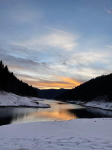 a river in the snow with the sunset in the background at Cabana Zimbru Transfagarasan in Arefu