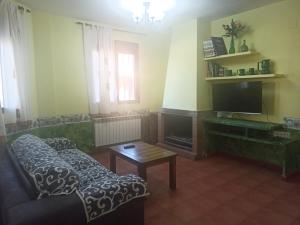 a living room with a couch and a tv at Casas Rurales Montemayor in Casas de Lázaro