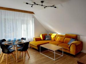 a living room with a yellow couch and a table at Westa Apartamenty in Krynica Zdrój