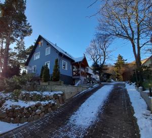 ein blaues Haus auf einer schneebedeckten Straße in der Unterkunft Ferienwohnung Kastanienblick mit Wlan in Bansin