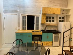 a kitchen with blue cabinets and a glass table at Linda casa em condomínio Sun House Maresias com piscina - 50 m da praia in Maresias