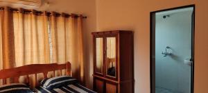 a bedroom with a bed and a mirror and a window at Esha Apartment in Calangute