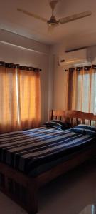 a bedroom with two beds with orange curtains at Esha Apartment in Calangute