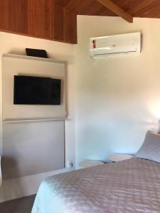 ein Schlafzimmer mit einem Bett und einem TV an der Wand in der Unterkunft Suíte Vista Mar Praia Estaleiro Balneário Camboriú in Balneário Camboriú