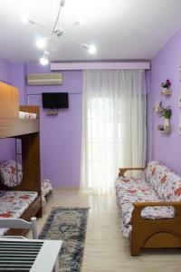 a bedroom with purple walls and a bed and a couch at Summer by the sea in Paralia Katerinis