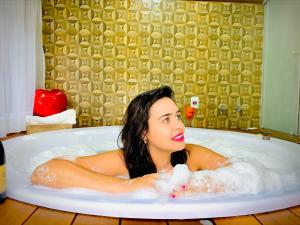 a woman laying in a bath tub with bubbles at Estalagem da Montanha in Monte Verde