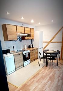 kuchnia z drewnianymi szafkami oraz stołem i krzesłami w obiekcie Apartament u Edka przy Dolnej II w Świeradowie Zdroju