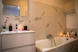 a bathroom with a tub and a sink with candles at Charmant studio à quelques pas du centre-ville in Troyes +6 photos