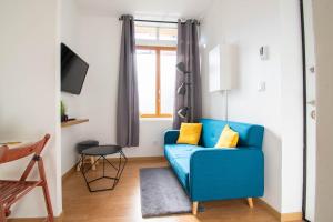 a living room with a blue couch and a window at Le Progrès in Villeurbanne