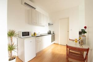 a kitchen with white cabinets and a table and a microwave at Le Progrès in Villeurbanne