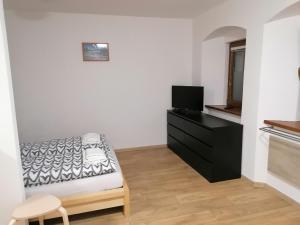 1 dormitorio con 1 cama, TV y vestidor en Apartmány Na náměstí en Boží Dar