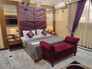 a hotel room with a bed and a red couch at Hotel Seven 7 in Karachi