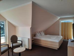 a bedroom with a bed and a chair and a window at Hotel Karl's Burg in Kolpinsee