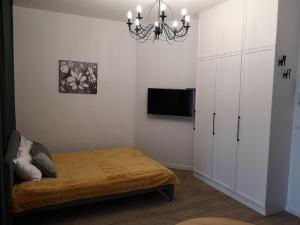 Schlafzimmer mit einem Bett, einem TV und einem Kronleuchter in der Unterkunft Solaris Apartments Self-Check-In in Oppeln