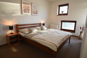 a bedroom with a large bed with a night stand and a lamp at Apartmán DOKY Lipno in Lipno nad Vltavou