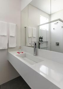une salle de bain blanche avec deux lavabos et un miroir dans l'établissement Pousada Gaúcha, à Bombinhas