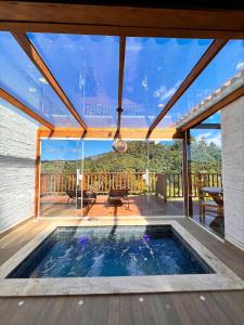 a swimming pool in a house with a large glass window at Estalagem da Montanha in Monte Verde