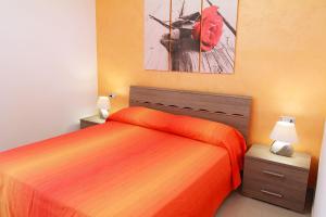 トッレ・サン・ジョヴァンニ・ウジェントにあるCase Vacanza Mare Del Sudのベッドルーム1室(オレンジ色のベッド1台付)が備わります。壁には絵画が飾られています。