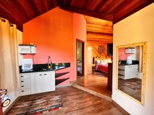 a kitchen with white cabinets and an orange wall at Estalagem da Montanha in Monte Verde
