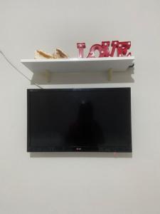 a flat screen tv on a wall with a shelf at Flat 09 in Conde
