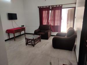 sala de estar con 2 sillas, mesa y TV en Villa Souhayl homestay, en Pondicherry