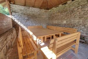 una mesa de madera y bancos en una habitación con una pared de piedra. en Chalupa Tomášek v blízkosti ski areálu, en Dolni Dvur